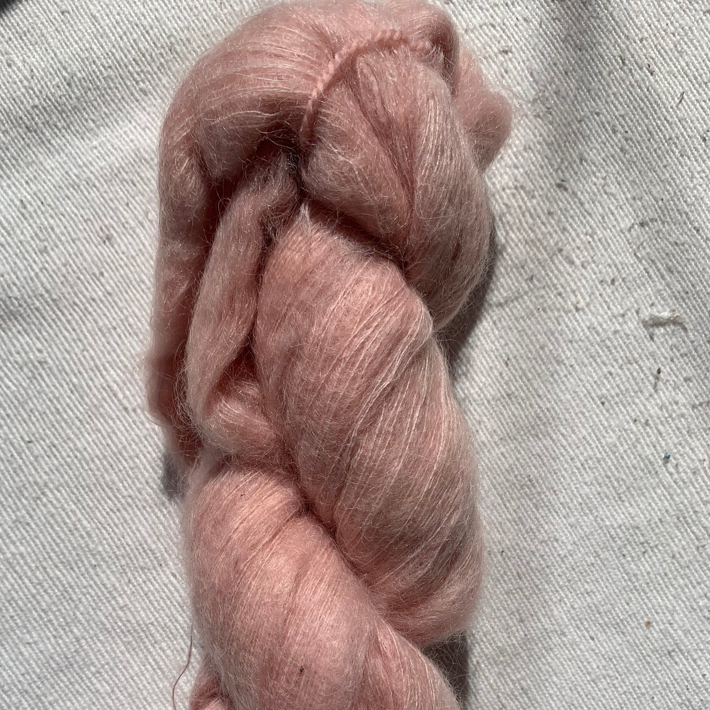 Pink skein of yarn on a textured gray surface