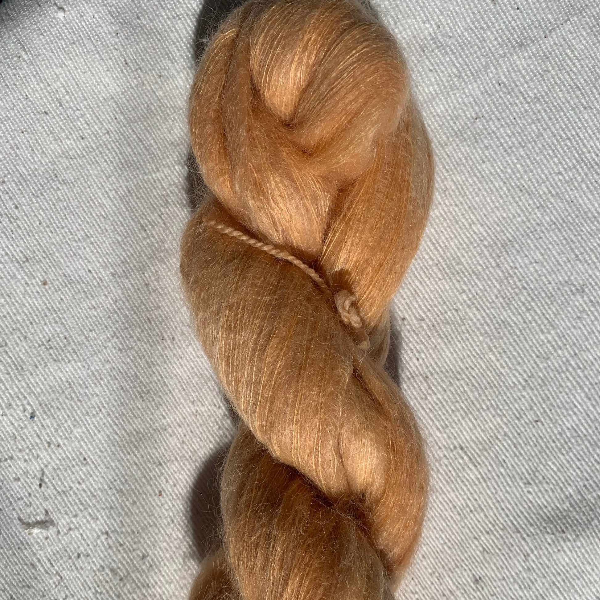 Fluffy mohair skein on textured gray surface